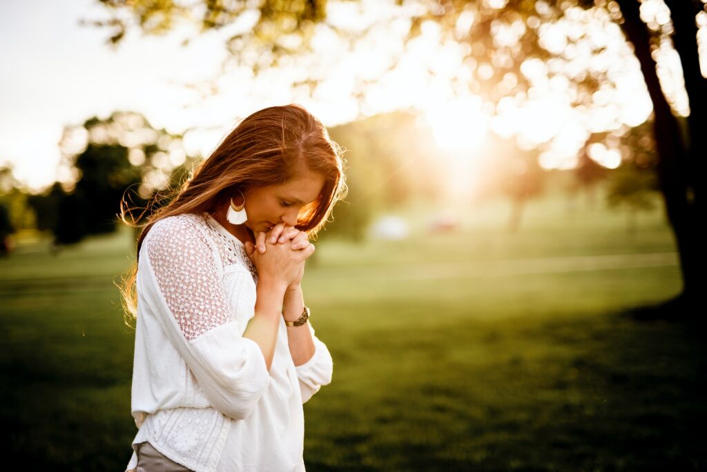 woman praying beside tree